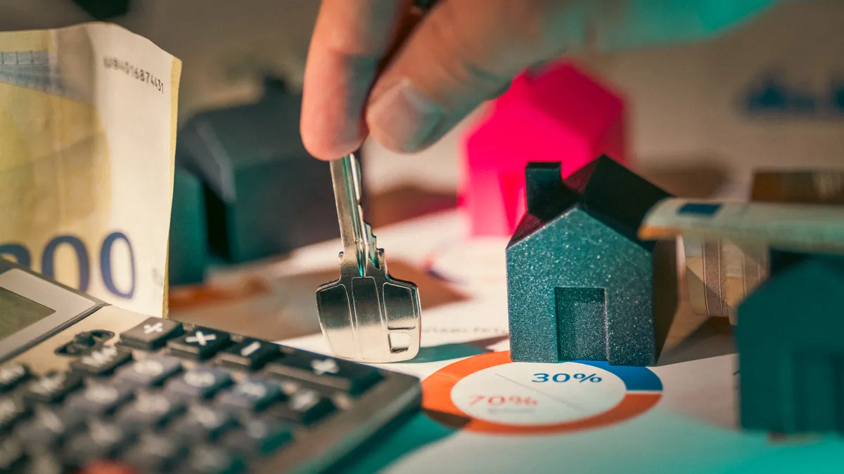 house keys beside a calculator and small house model